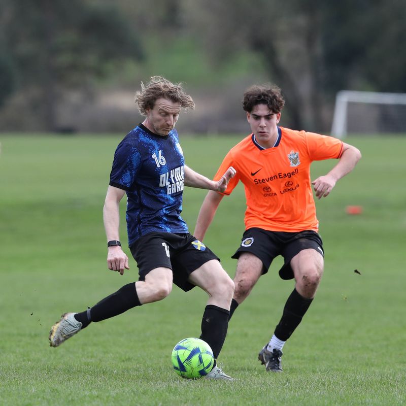A player in navy on the ball against an opponent in orange